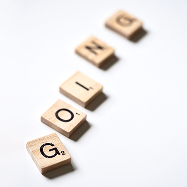 A series of Scrabble tiles arranged diagonally on a white background, spelling the word "GOING".